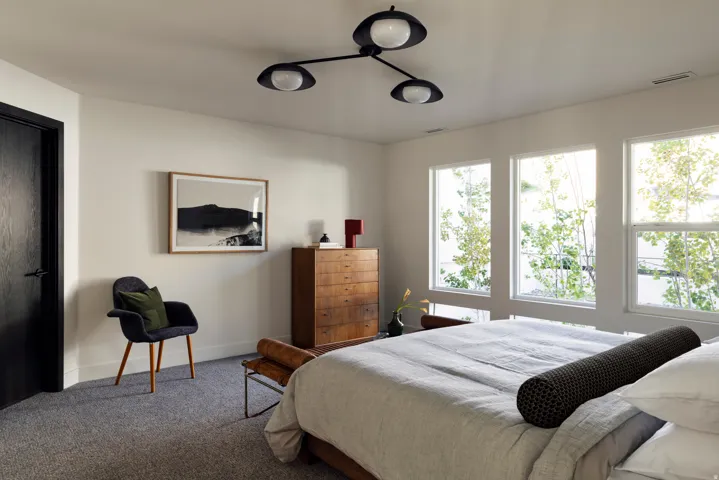 Recessed ceiling vents, dark wood-grain door, contemporary ceiling light fixture, light-toned wall paint, and three large windows