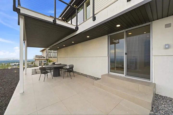 Covered patio with integrated recessed lighting, leading to a sliding glass door entry