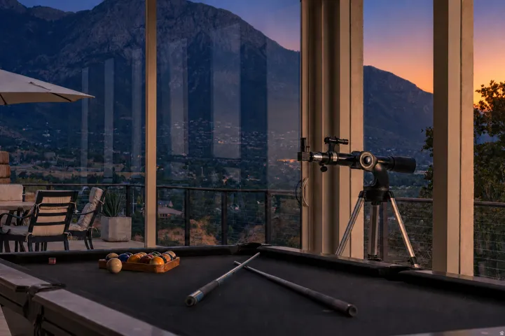 Expansive glass paneling with a mountain backdrop, complemented by an outdoor balcony featuring a metal railing