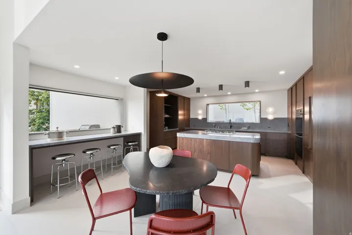 Integrated kitchen and dining area featuring wood-finish cabinetry, a central island with a light-toned countertop, a built-in oven, and recessed lighting