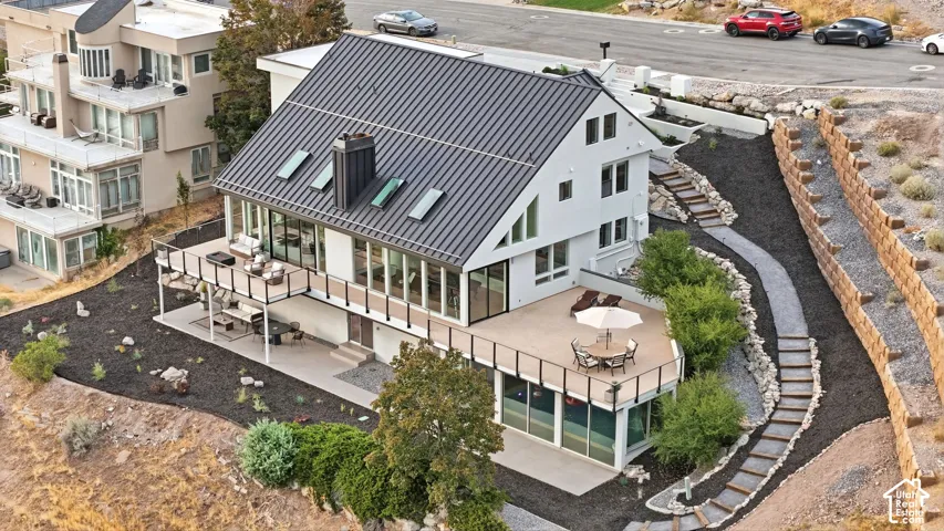 Modern exterior featuring a dark metal roof, multiple skylights, and a spacious multi-level deck with glass panel railings
