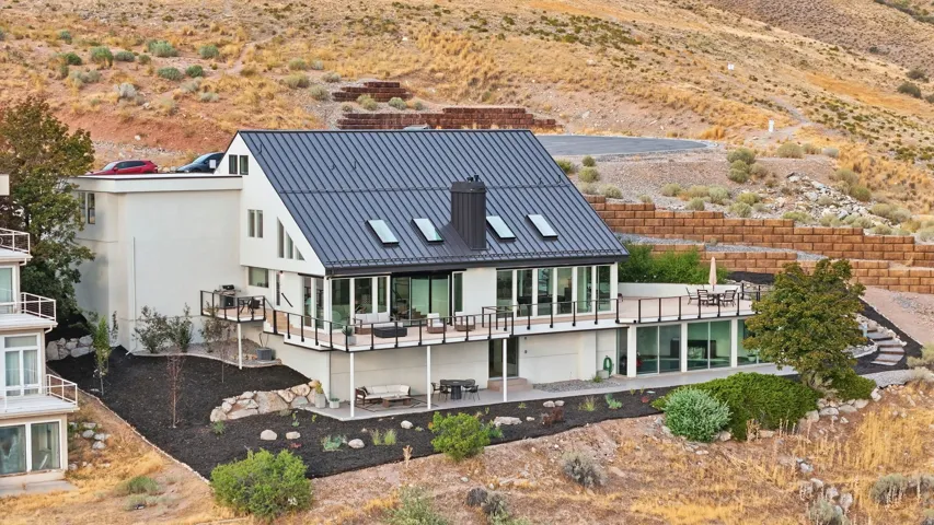 Modern architectural design featuring a dark metal roof, multiple skylights, and expansive glass doors