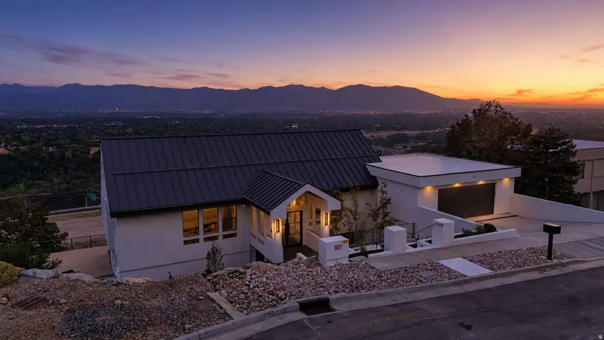 Modern exterior with a dark metal roof, white stucco facade, and an integrated garage