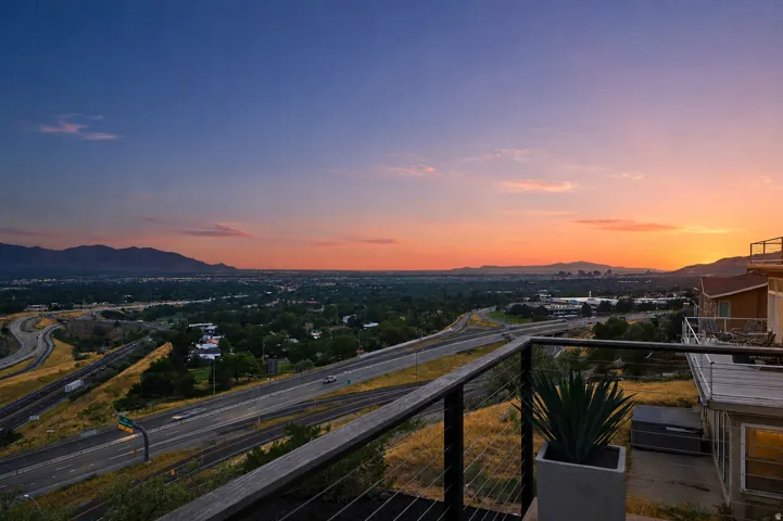 Deck with cable railing system overlooking a wide valley, distant cityscape, and mountainous horizon