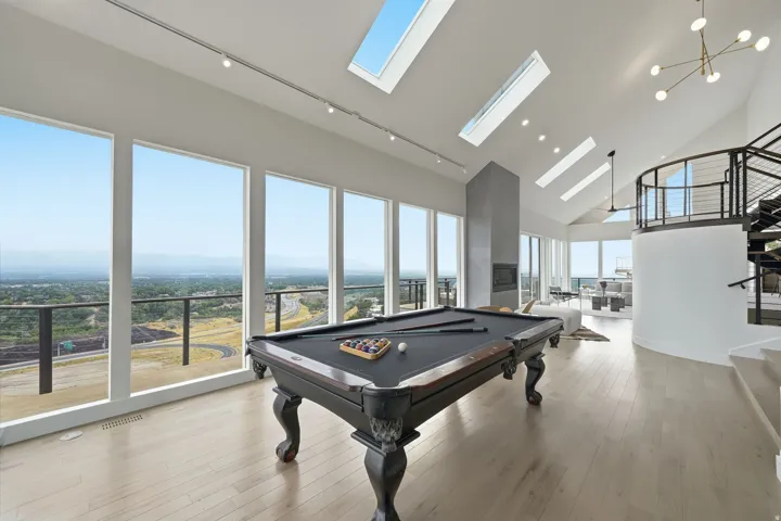 Vaulted ceilings, skylights, expansive windows, light wood-finish flooring, and a contemporary spiral staircase with metal railings