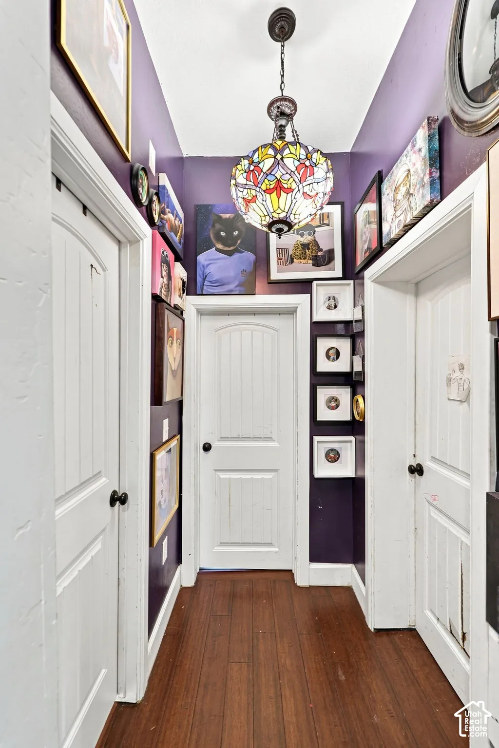 Wood-finish flooring with a multi-door hallway and a colorful stained-glass chandelier