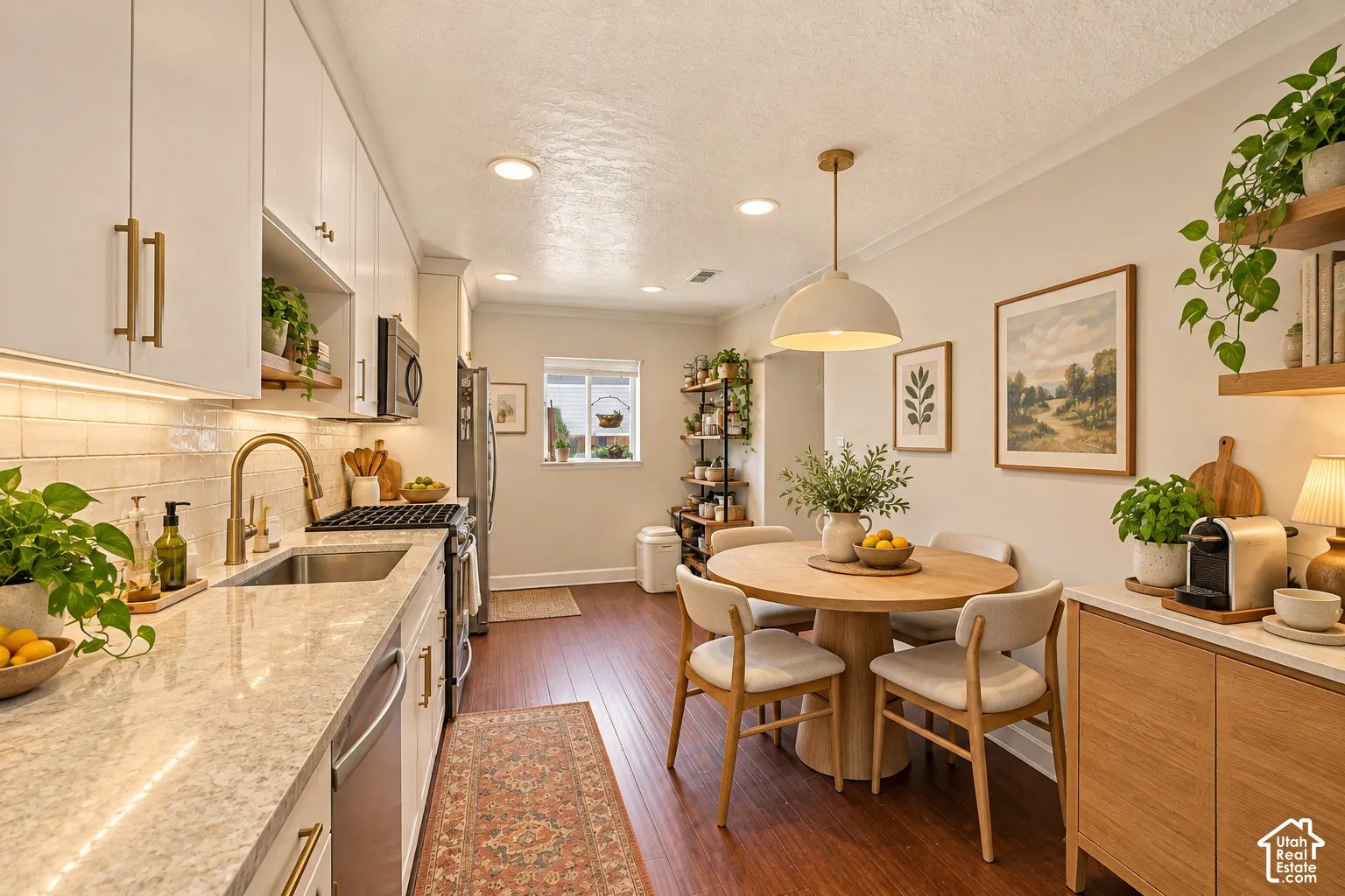 White cabinetry with brass hardware, light-toned backsplash, and light-colored countertops