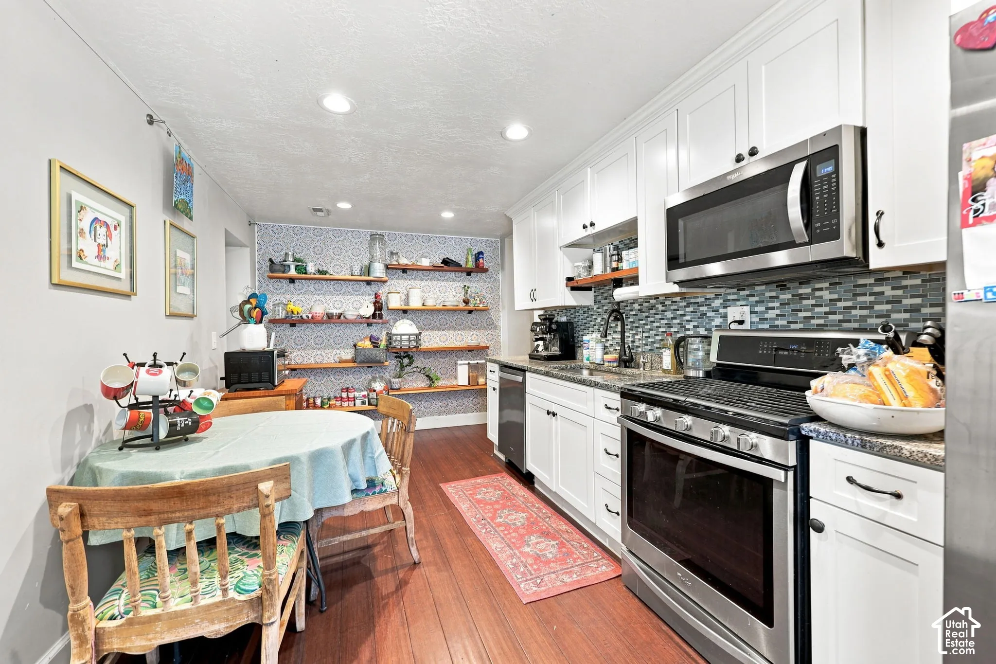 White shaker cabinetry, stainless steel appliances, wood-finish flooring, mosaic tile backsplash, and recessed lighting
