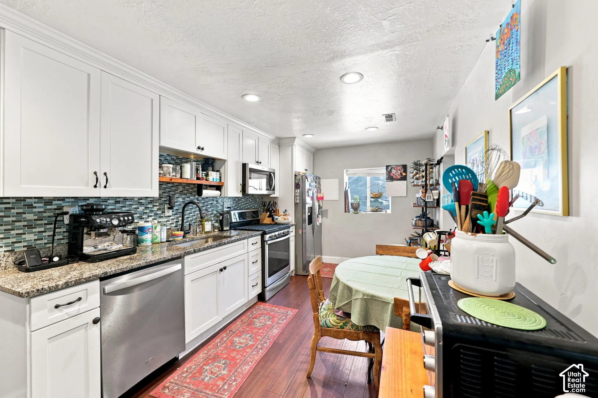 White shaker cabinetry, granite countertops, tile backsplash, stainless steel appliances, and recessed lighting