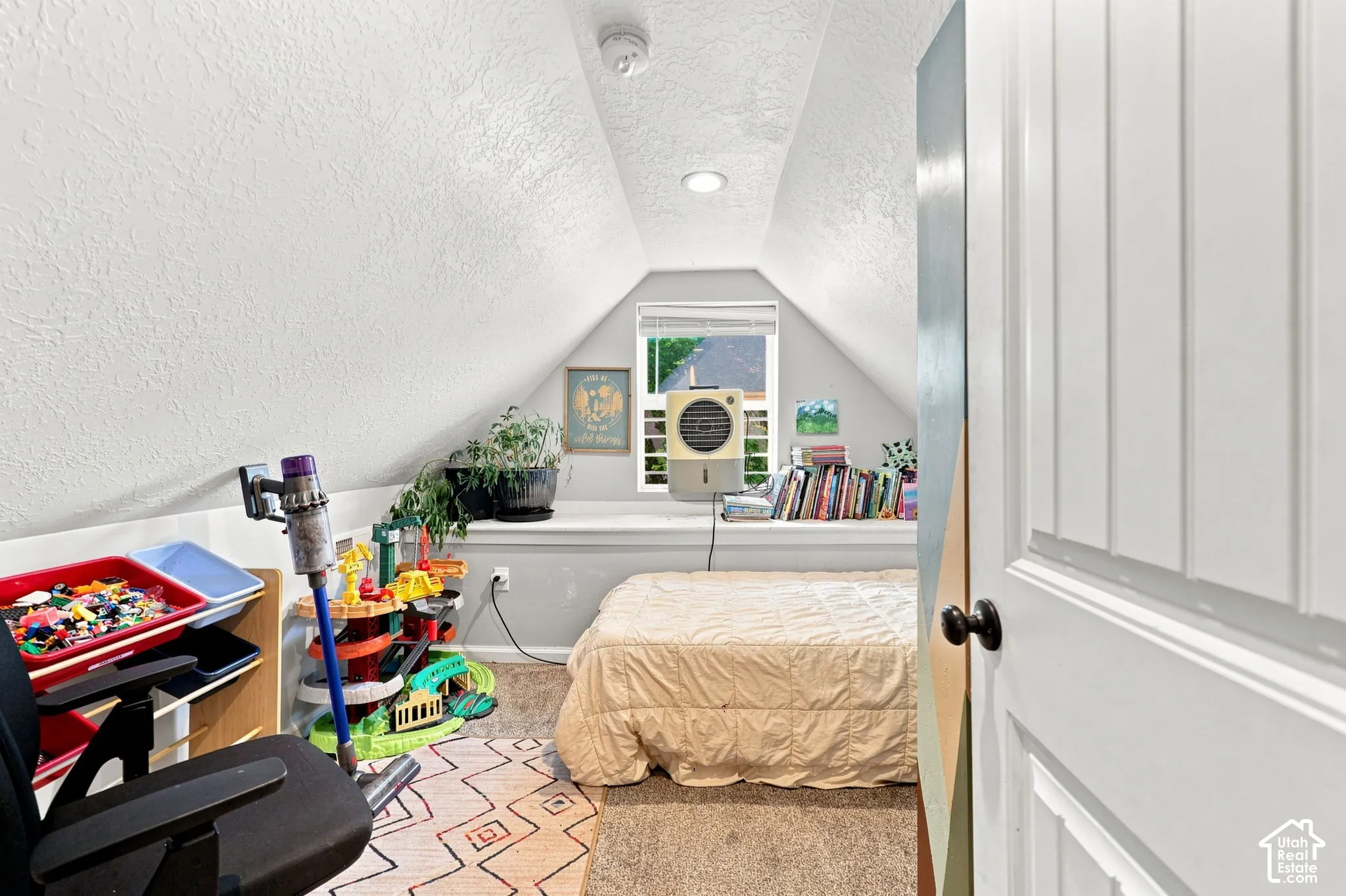 Attic space featuring sloped ceilings, recessed lighting, and a white paneled door with a dark knob