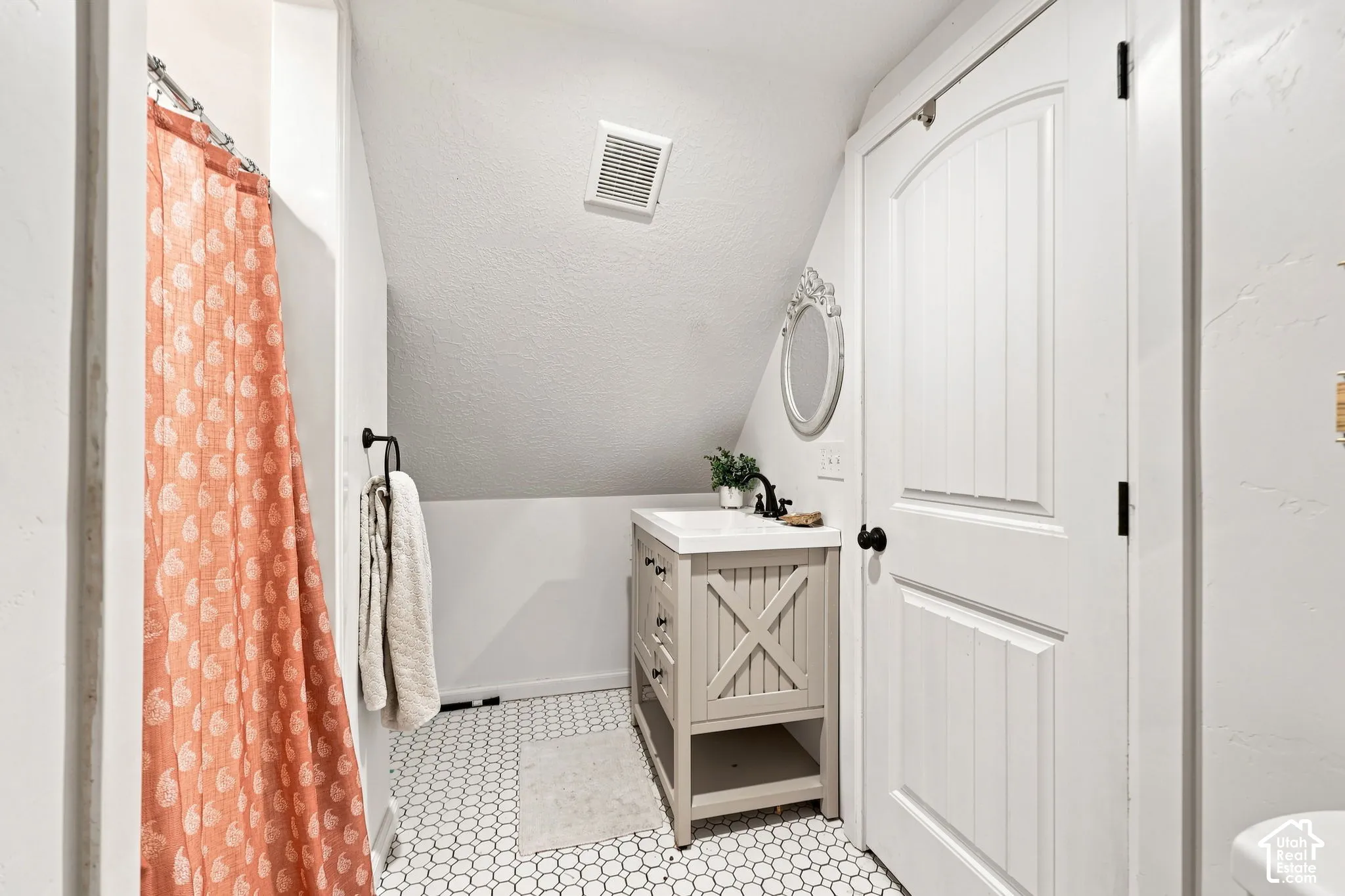 Light-toned vanity with an integrated sink, black fixtures, and a decorative mirror