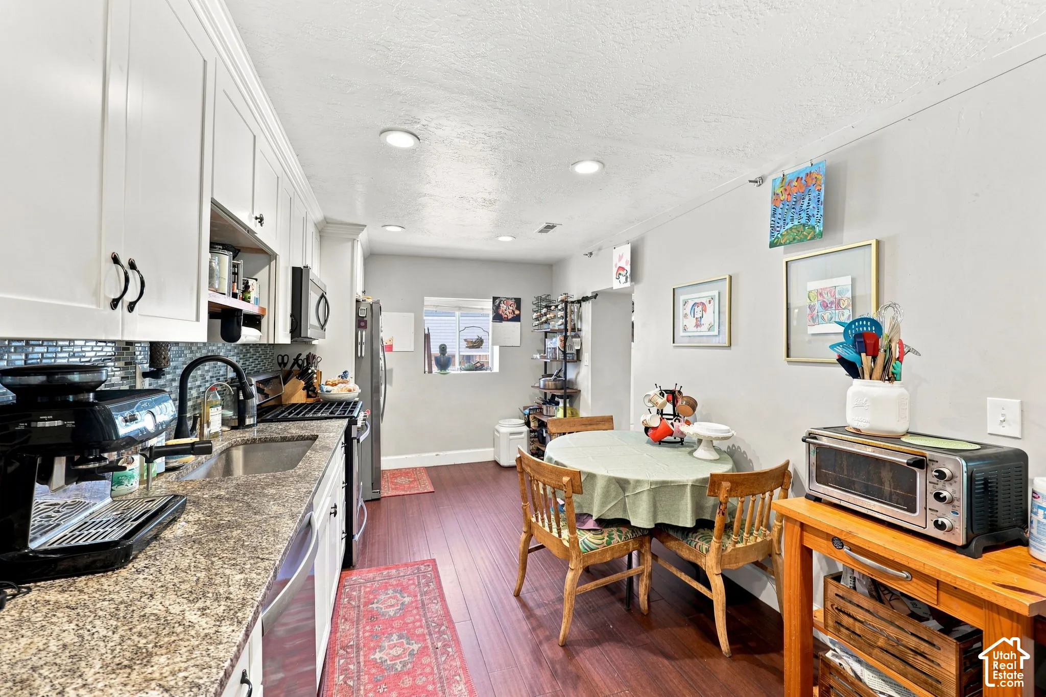 Kitchen featuring white cabinetry, granite-style countertops, stainless steel appliances, and wood-finish flooring
