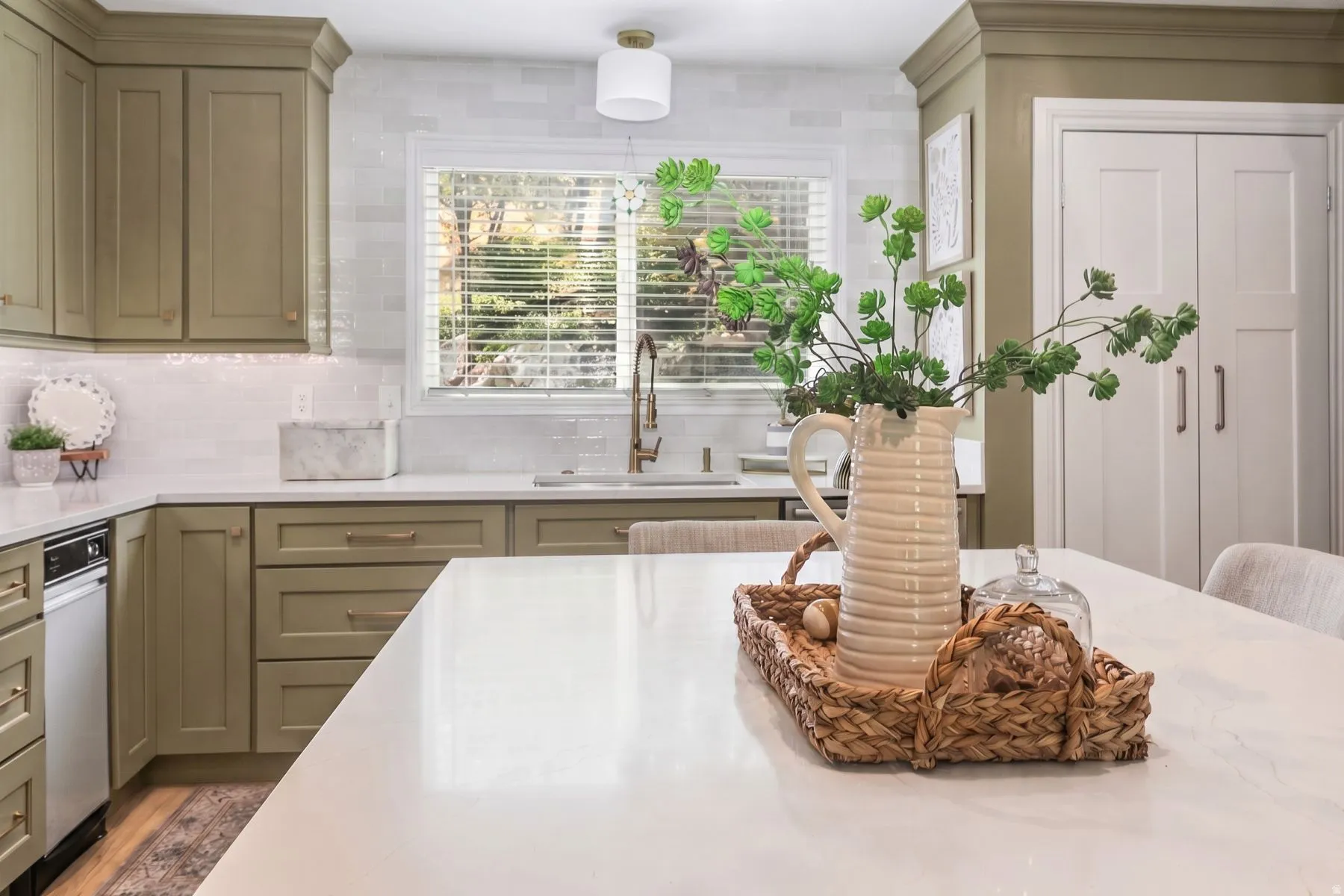 Sophisticated kitchen featuring custom cabinetry with warm wood-finish, white quartz countertops, and a large waterfall-edge island