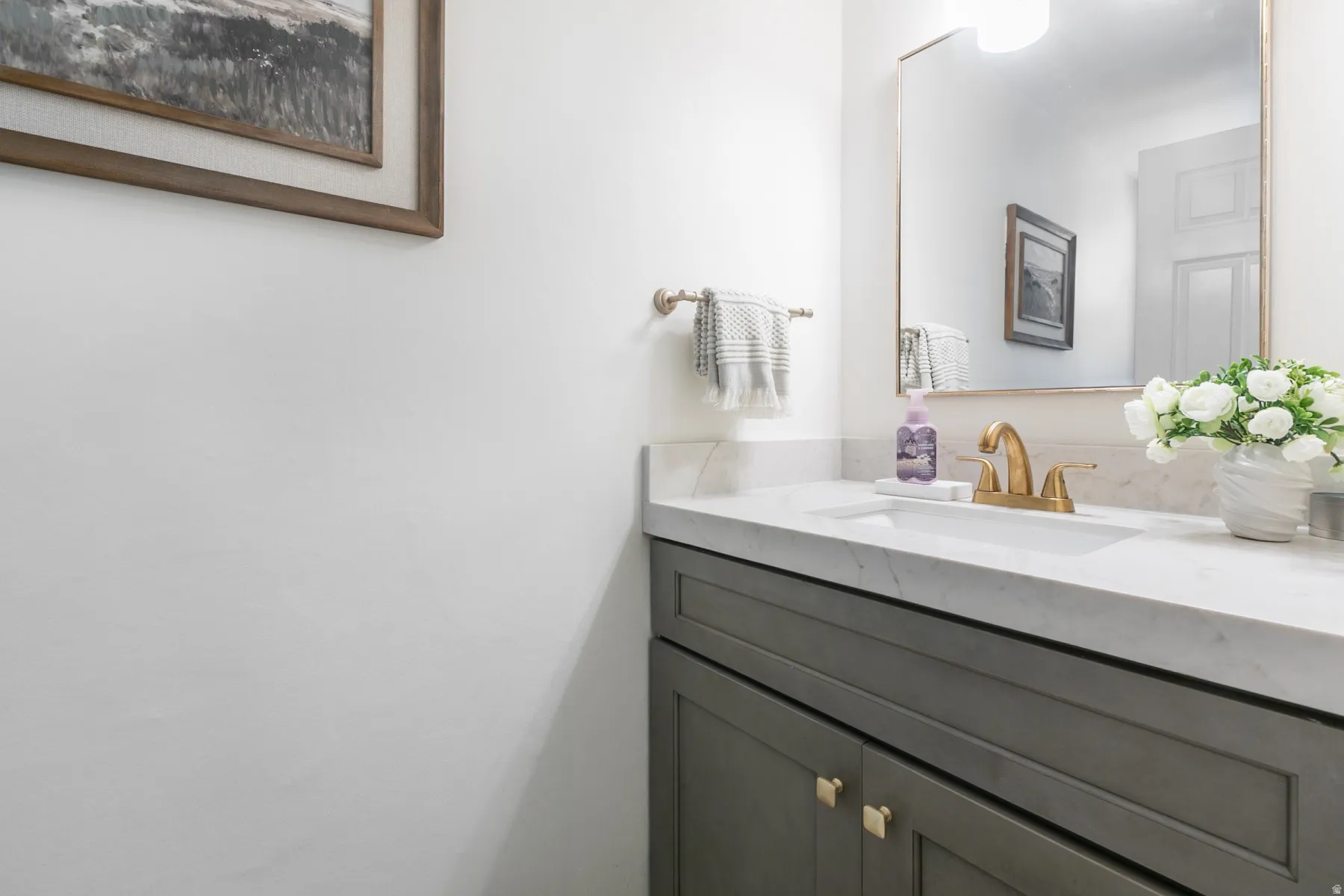 Vanity featuring a stone countertop, an undermount sink, and a gold-tone faucet