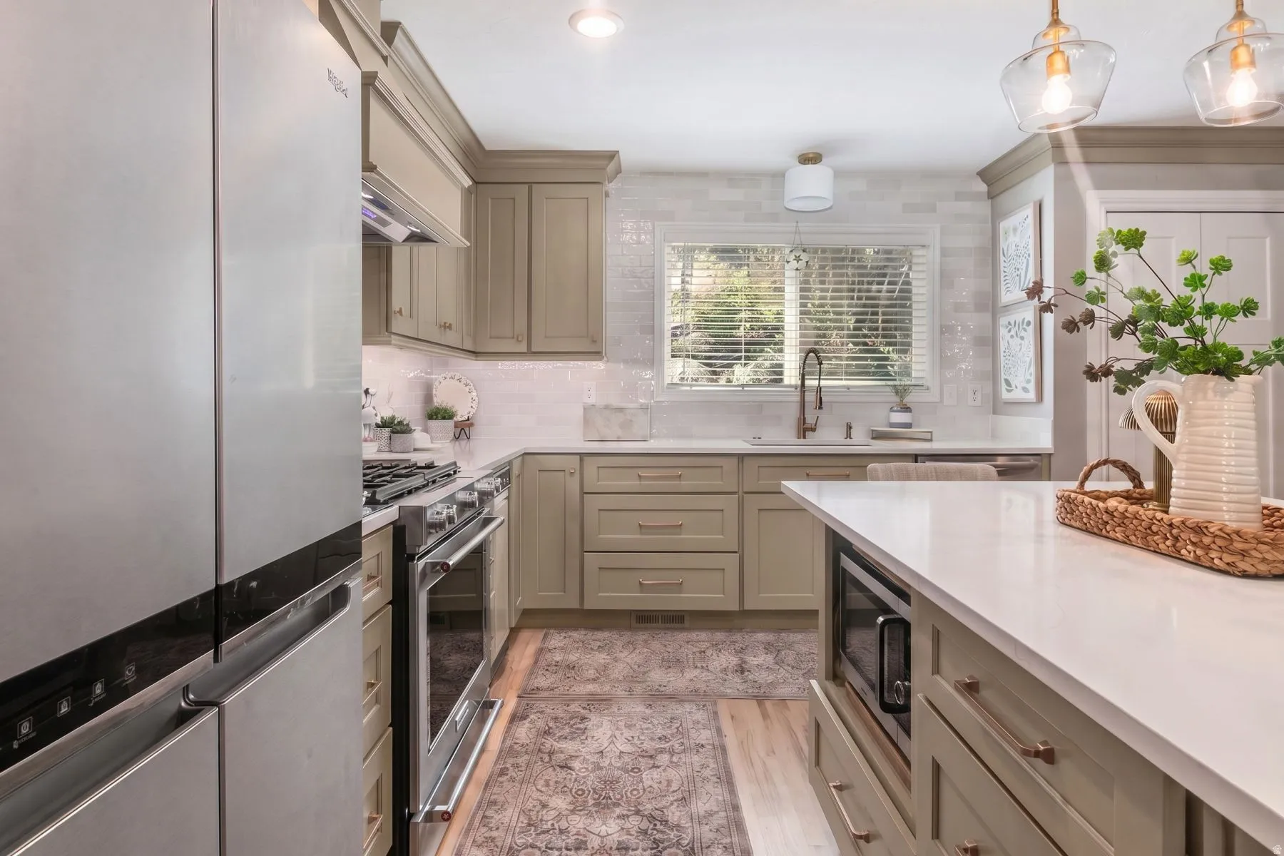 Galley kitchen featuring custom cabinetry with soft-close drawers, quartz countertops, stainless steel appliances including a gas range and built-in microwave, pendant lighting, and abundant natural light from multiple windows