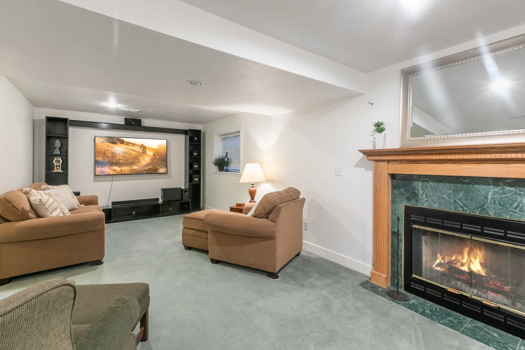 Fireplace with a wood mantel and green stone surround, built-in entertainment center, recessed lighting, and light-colored carpeting