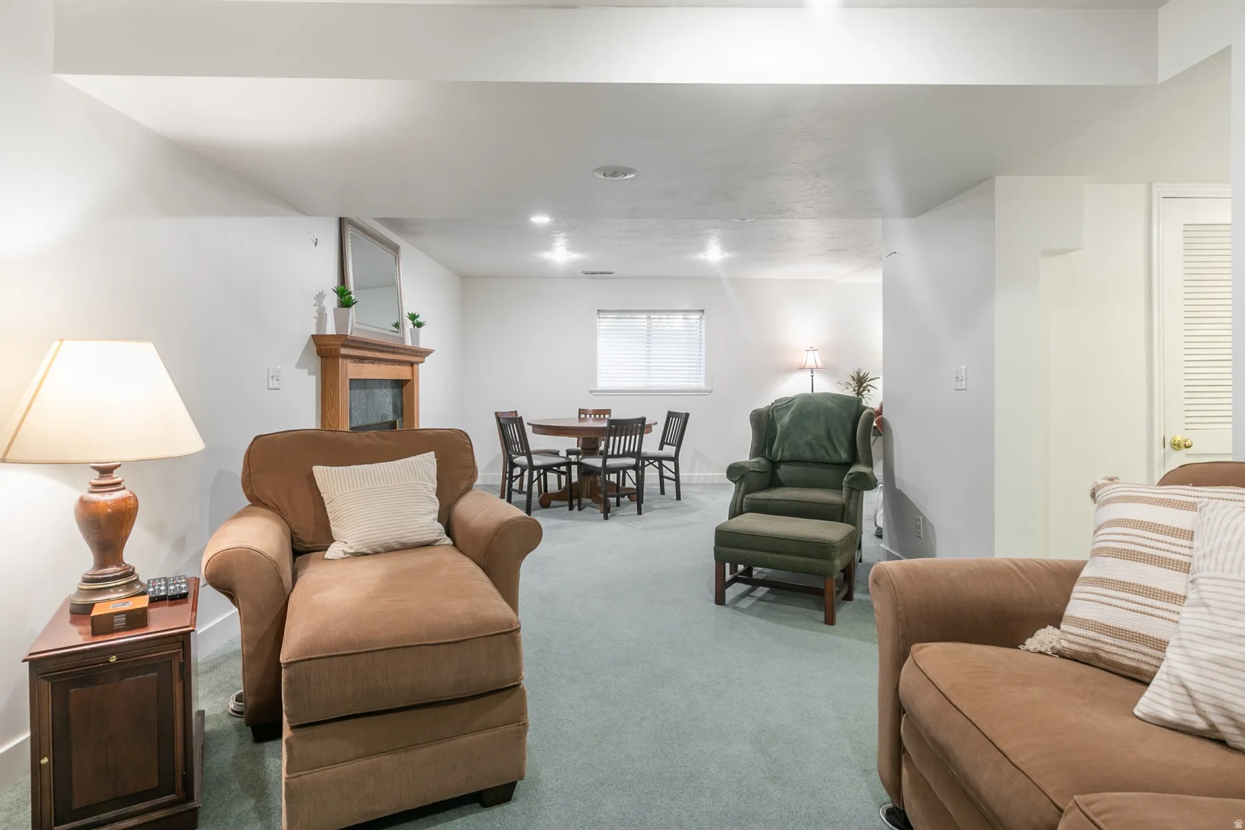 Spacious finished basement featuring multiple seating areas, recessed lighting throughout, neutral carpeting, and a dining zone with wood-finish table and chairs