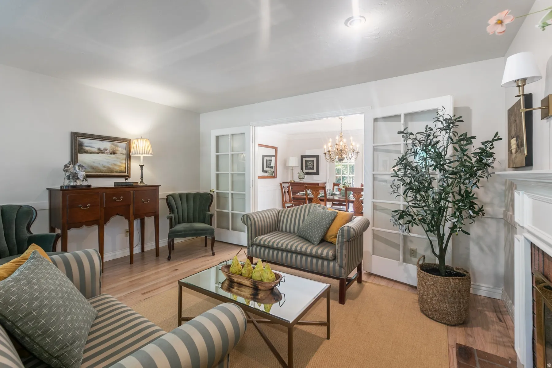 Elegant formal living area featuring hardwood flooring, a decorative fireplace with white surround and mantel, crown molding, recessed lighting, and French doors opening to adjacent spaces