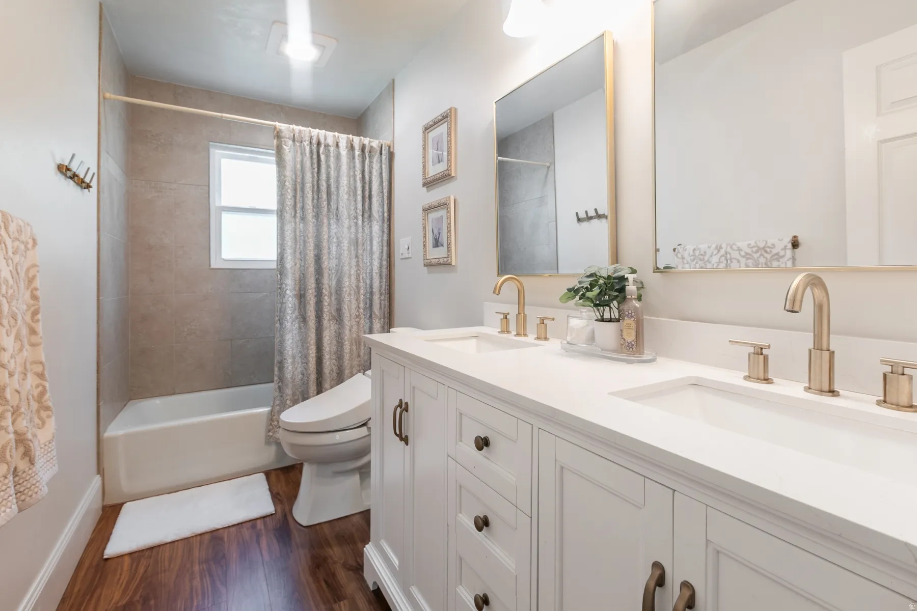Double vanity with white cabinetry, quartz countertop, and gold-finish fixtures
