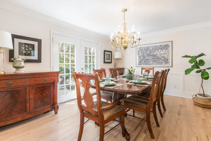 Elegant dining room showcasing rich wood-finish flooring, a formal dining table with coordinating chairs, and a crystal chandelier