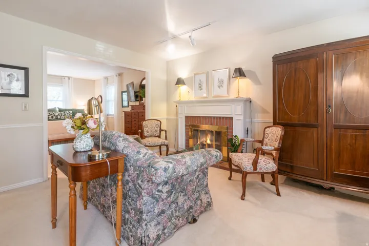 Living room featuring a brick fireplace with a white mantel, track lighting, and carpet flooring