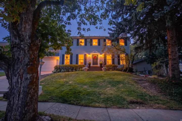 Two-story residence featuring a front entry with sidelights, a two-car garage, and mature landscaping