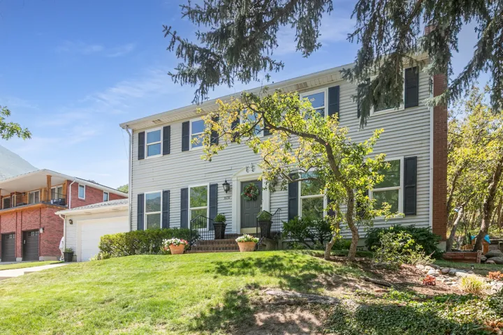 Two-story residence with light-toned siding and dark shutters, featuring a two-car garage