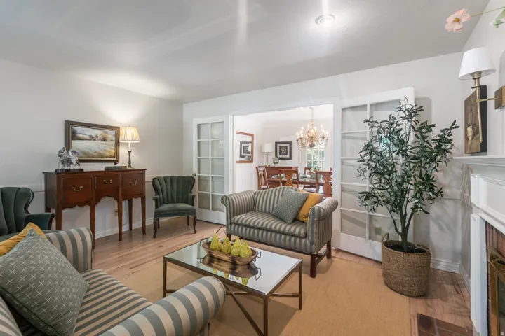 Elegant formal living area featuring hardwood flooring, a decorative fireplace with white surround and mantel, crown molding, recessed lighting, and French doors opening to adjacent spaces