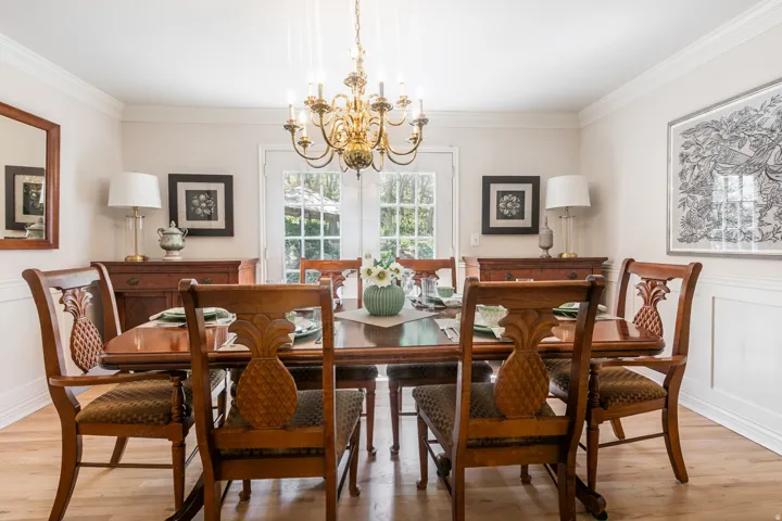 Elegant dining space featuring a brass chandelier, French doors, wood-finish flooring, and crown molding