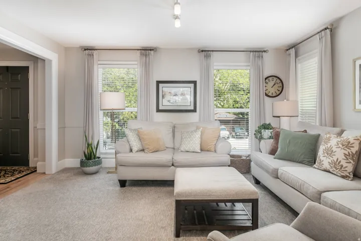 Bright and airy living room featuring multiple large windows with natural light, neutral wall finishes, and hardwood-finish flooring throughout