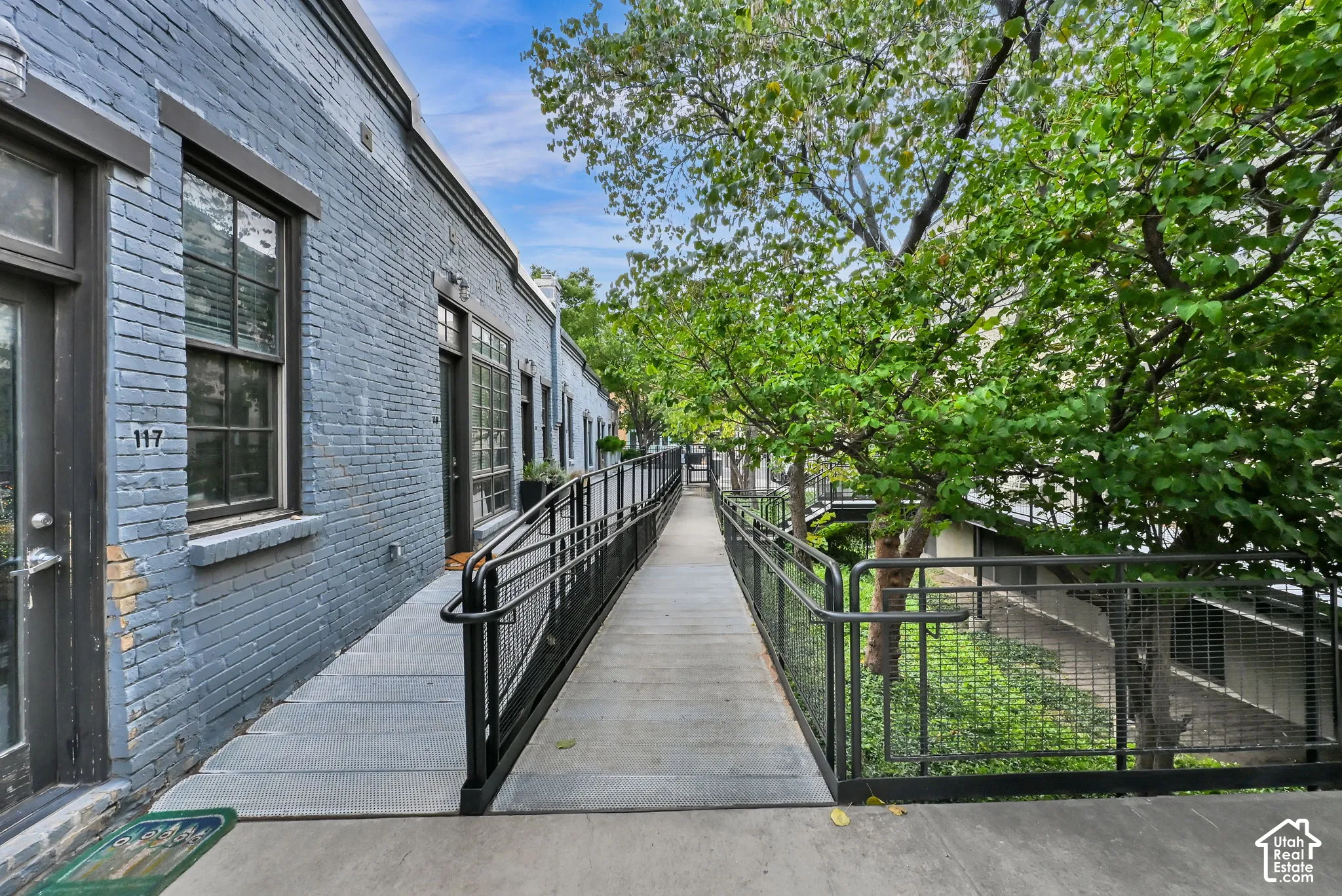 Modern brick residence with a covered entry walkway featuring black metal railings and a gated entrance
