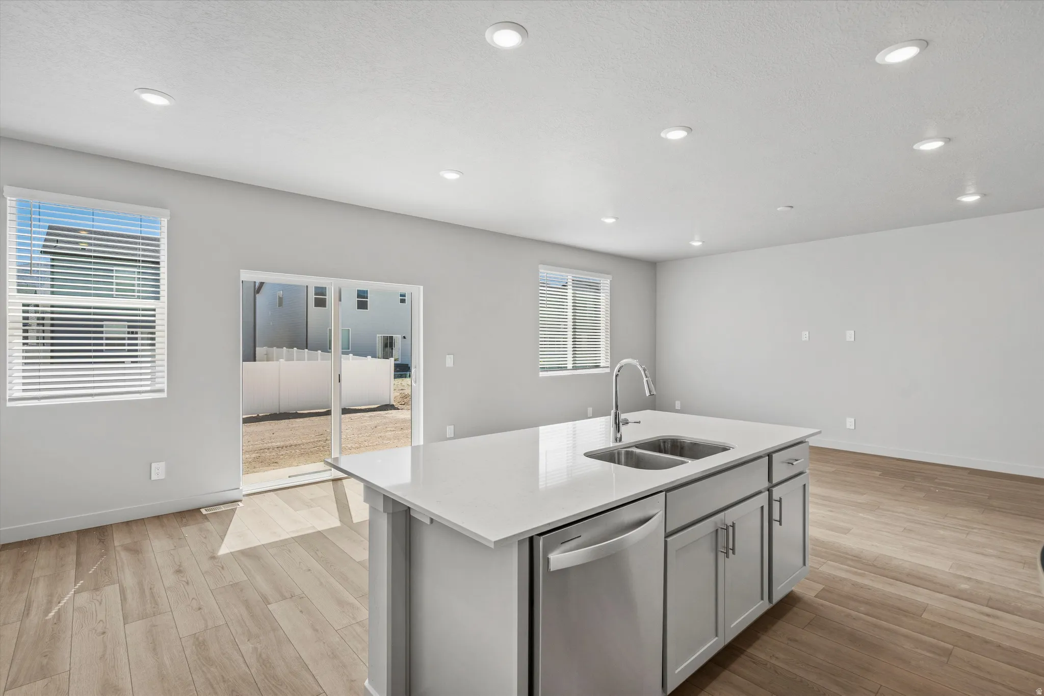 Modern kitchen island with stainless steel appliances, white quartz countertops, and ample storage cabinetry