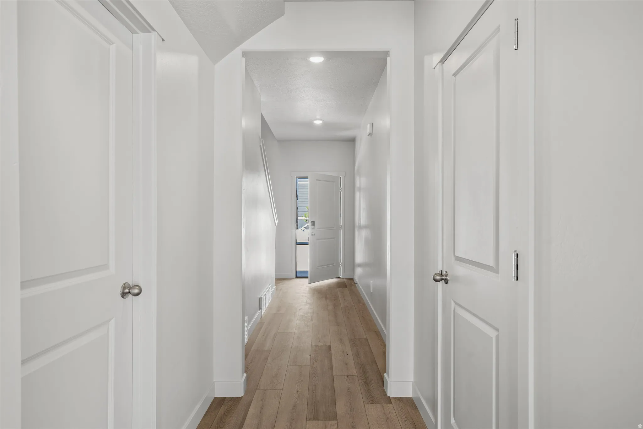 Hallway featuring light wood-finish flooring, recessed lighting, and white paneled doors