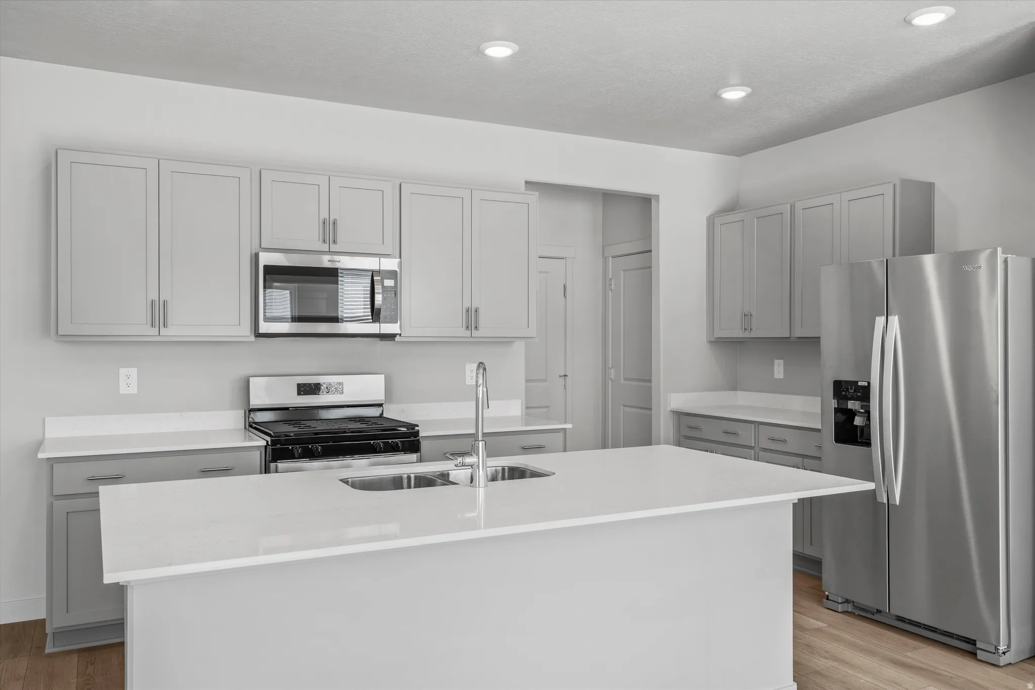 Kitchen featuring a large island, stainless steel appliances, light gray cabinetry, recessed lighting, and wood-finish flooring
