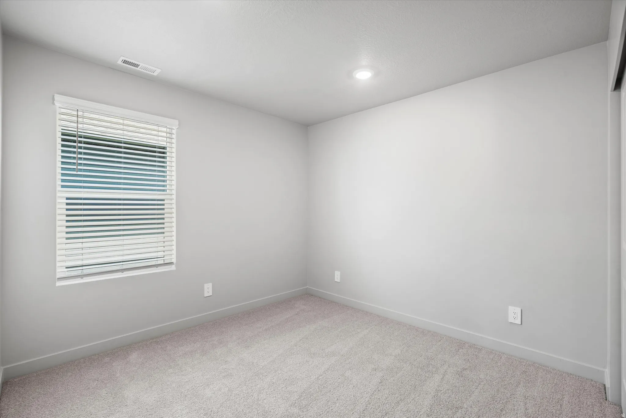 Recessed ceiling lighting, window with blinds, light-toned carpeting, and neutral wall finish