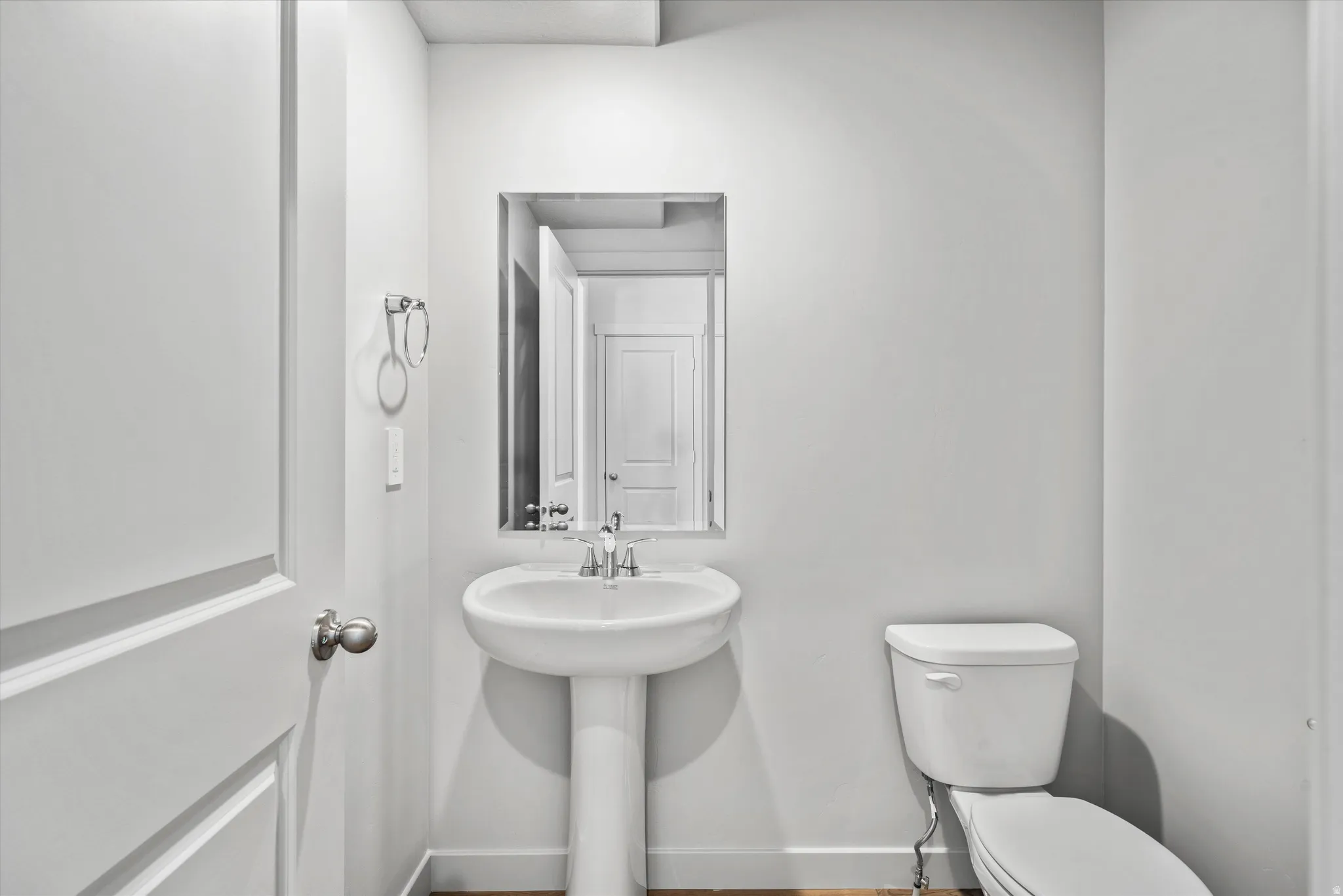 Pedestal sink with chrome faucet, framed mirror, and white toilet