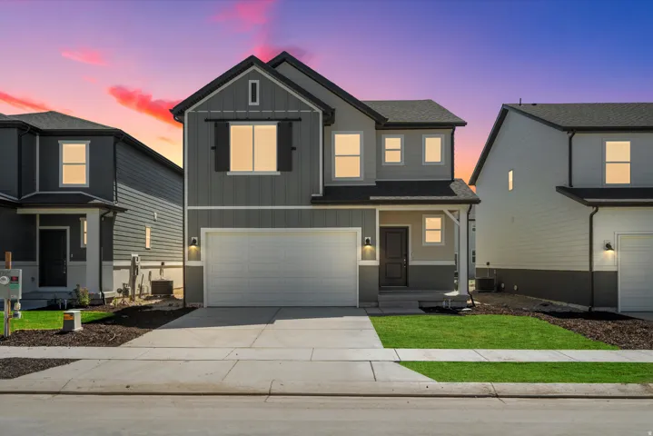 Two-story residence featuring a two-car garage, covered entry, and dark-paneled garage door with windows