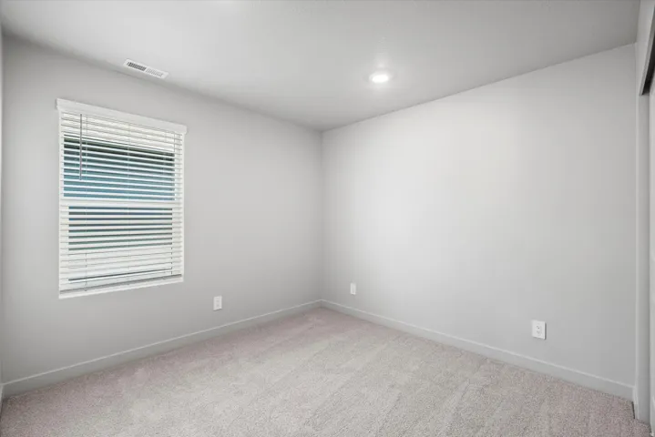 Recessed ceiling lighting, window with blinds, light-toned carpeting, and neutral wall finish