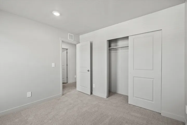 Recessed ceiling lighting, light gray wall paint, carpeting, white interior doors, and a sliding closet door