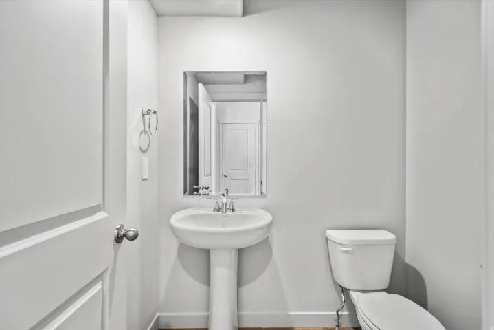 Pedestal sink with chrome faucet, framed mirror, and white toilet