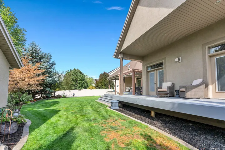 Expansive backyard with manicured lawn, mature landscaping, and black mulch hardscaping.