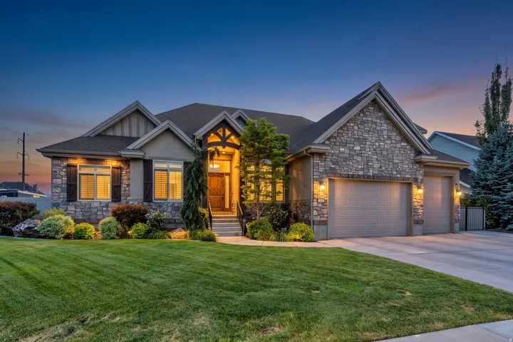Stone and stucco exterior, arched portico with wood beam accents, multiple gables, attached three-car garage, and established landscaping.