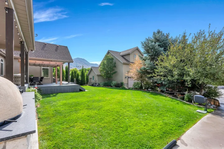 Expansive green lawn, a covered patio, and a separate elevated deck with a pergola.