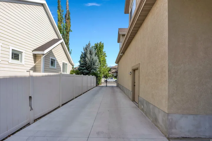 Concrete side passage with vinyl privacy fencing, mature landscaping.  LOTS of parking for multiple vehicles.  Driveway access to back yard.