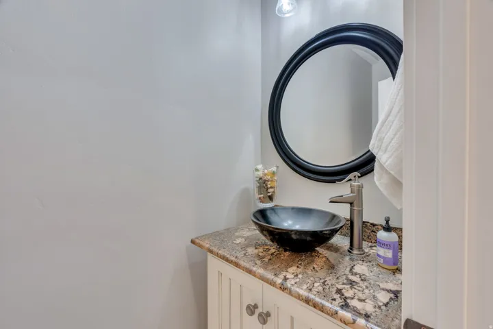 Elegant powder room featuring a granite-topped vanity with vessel sink, polished nickel faucet, and soft-close cabinetry.