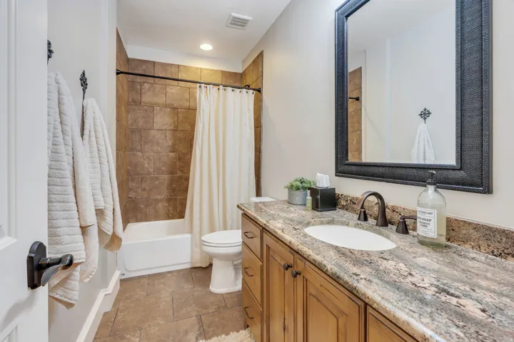 Spa-inspired primary bathroom featuring a wood-finish vanity with granite countertop, dual-sink configuration, and oil-rubbed bronze hardware.