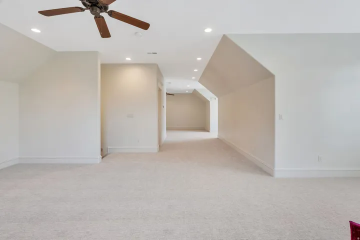 Spacious bonus room with vaulted ceilings, ceiling fan, recessed lighting, and brand new neutral carpet.