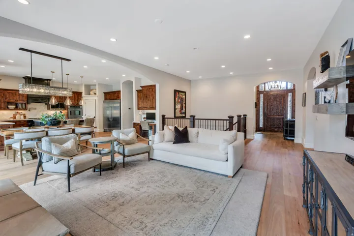 Hardwood flooring throughout, recessed lighting, and an expansive kitchen featuring wood cabinetry, stainless steel appliances, and a large central island with pendant lighting.