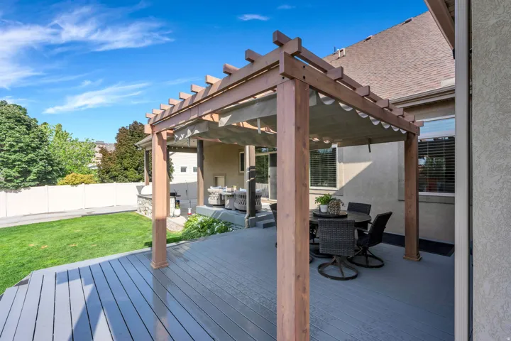 Spacious composite deck and pergola structure featuring stained wood-finish framing with lattice detailing, composite decking in neutral tones, and integrated seating areas.