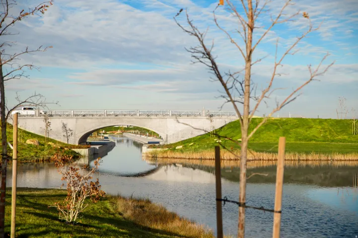 Reflecting water feature with a contemporary arched bridge and lush green embankments